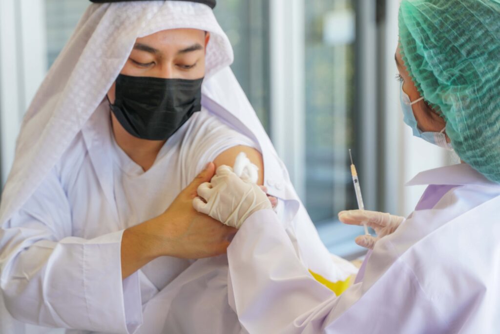A person receiving a vaccine at a clinic in Crumpsall, possibly for Umrah travel.